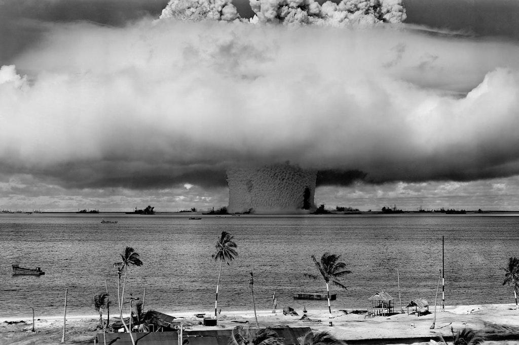 Photo of an explosion on a beach to connect to the Oppenheimer music with