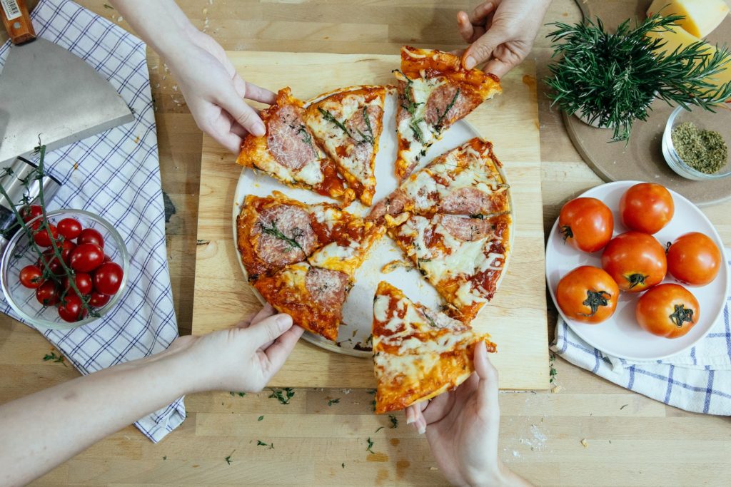 Group of friends practicing portion control by making enough delicious homemade pizza for two slices each