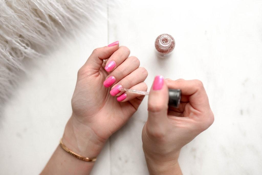 Image of woman painting her nails pink inspired by the Barbie Pink Nails trend